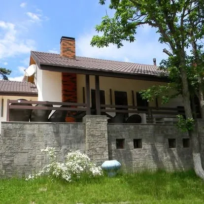 Residential home with grey stone retaining wall, porch, and landscaped yard